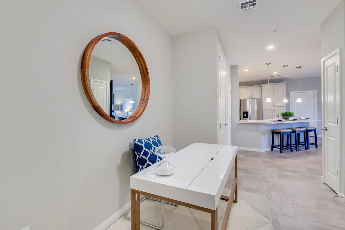 A welcoming entryway scene featuring a round mirror above a console table, a decorative chair, and tasteful decor. The space radiates hospitality and sets the tone for arriving home after exploring the neighborhood.