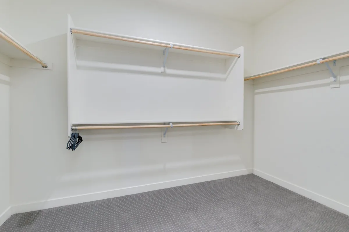 A spacious walk-in closet with organized shelving and ample hangers. The area provides plenty of storage for clothing and personal items, emphasizing a clutter-free, extended-stay-friendly environment.