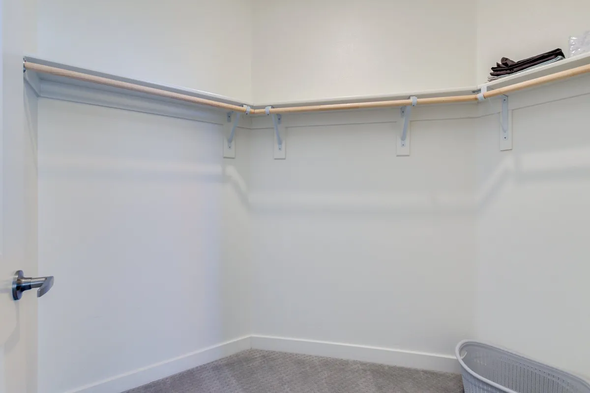 A calm and functional storage space with shelves, a carpet, and a basket, designed for organizing belongings and storing seasonal items. The neutral color palette and simple layout emphasize order and efficiency.