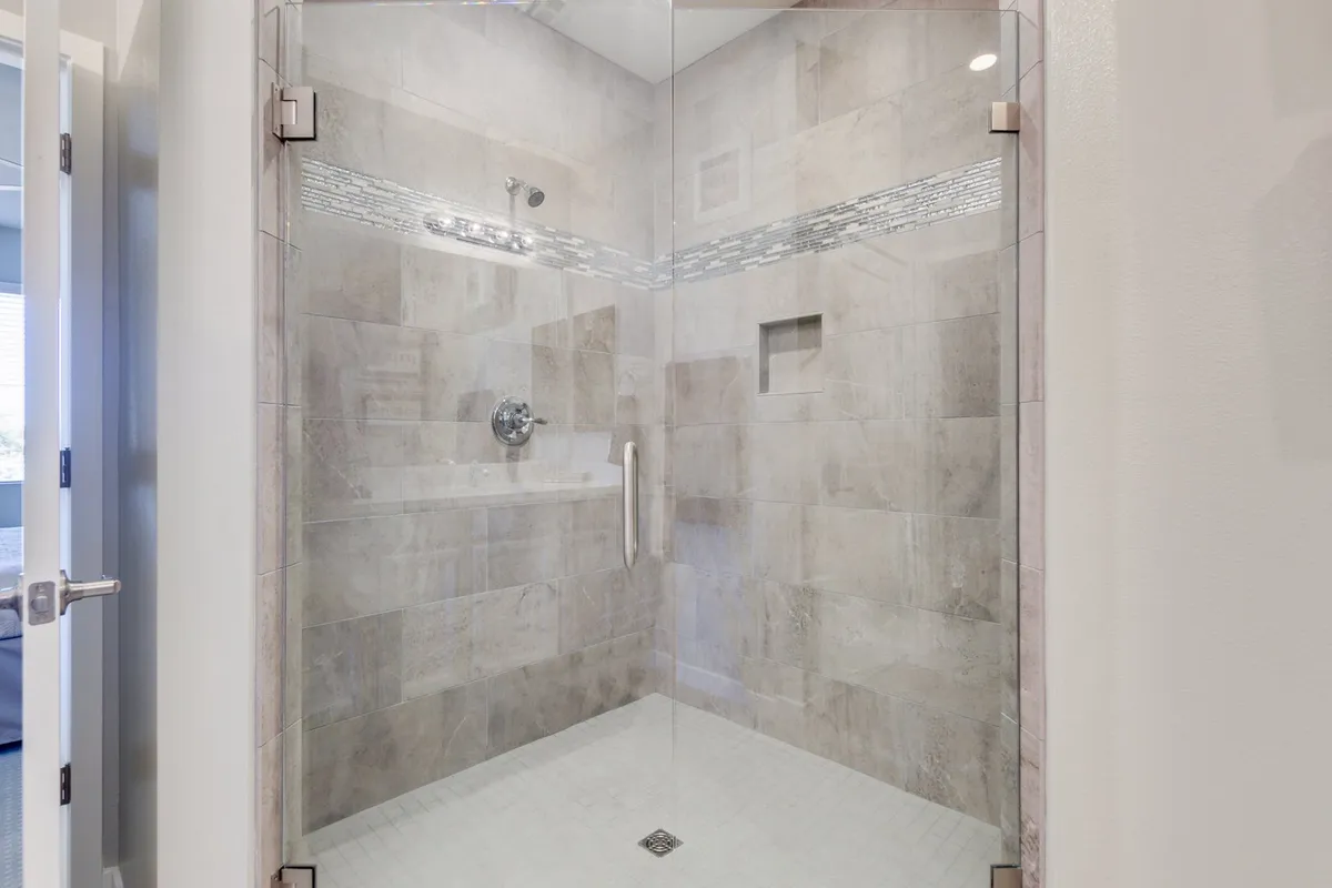 A modern bathroom featuring a glass shower enclosure, textured tiles, and sleek fixtures. The tranquil mood invites thoughts of relaxation and rejuvenation, reminiscent of spa facilities.